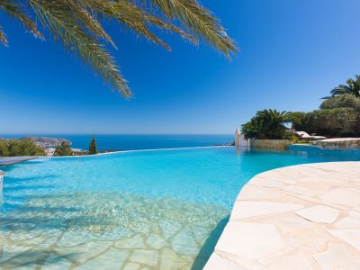 Piscine à débordement avec une entrée en pente douce et margelles en pierre claire, offrant une vue imprenable sur la mer Méditerranée.