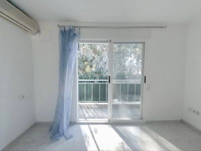 Chambre lumineuse avec climatisation et accès direct à une terrasse privée. Sol carrelé clair et vue sur la verdure extérieure.