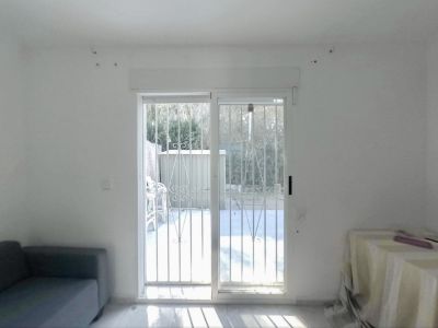 Pièce spacieuse avec portes coulissantes vitrées et barreaux de sécurité, offrant un accès direct au jardin privé, baignée de lumière naturelle sur le sol clair.