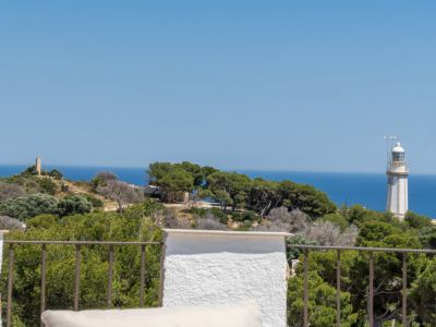 Vue panoramique depuis la terrasse avec balustrade métallique, présentant la mer Méditerranée, un phare et une tour de pierre au loin.