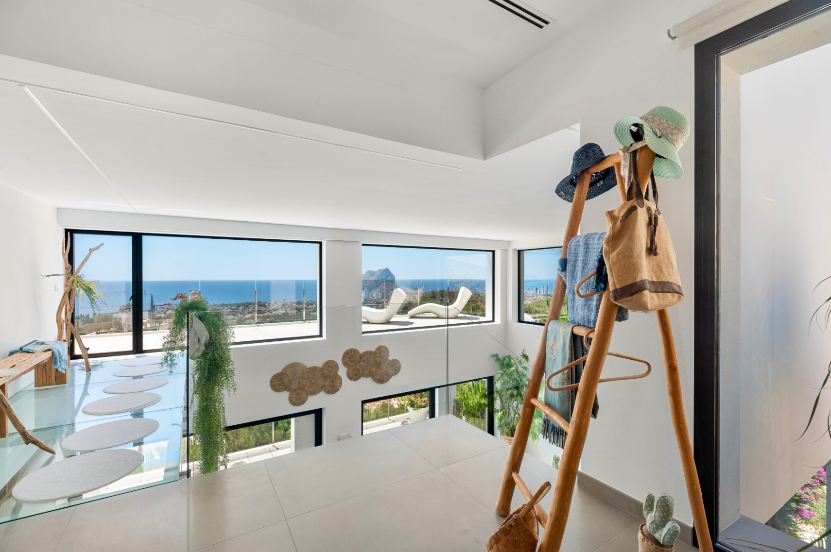 Étage supérieur avec carrelage clair et balustrade en verre. Vues panoramiques sur la mer et le Peñon de Ifach par de grandes fenêtres. Comprend une passerelle en verre à marches ovales et un porte-manteau en bois. Étage supérieur avec carrelage clair et balustrade en verre. Vues panoramiques sur la mer et le Peñon de Ifach par de grandes fenêtres. Comprend une passerelle en verre à marches ovales et un porte-manteau en bois.