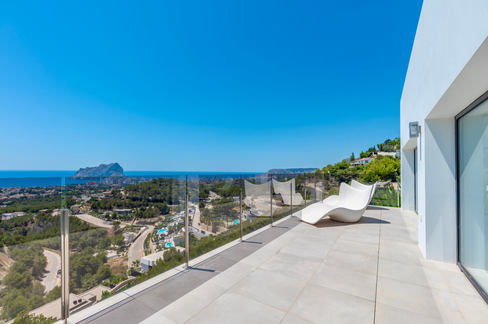 Grande terrasse extérieure carrelée de tons clairs, agrémentée d'une chaise longue blanche moderne et d'une balustrade en verre. Profitez des vues panoramiques sur la mer, le Peñón de Ifach et Calpe. Grande terrasse extérieure carrelée de tons clairs, agrémentée d'une chaise longue blanche moderne et d'une balustrade en verre. Profitez des vues panoramiques sur la mer, le Peñón de Ifach et Calpe.