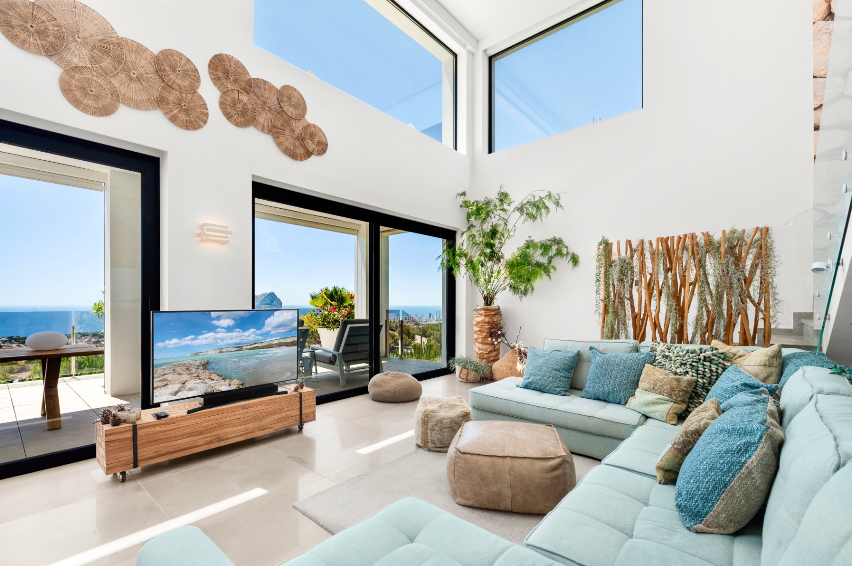 Salon lumineux avec de hauts plafonds et de grandes baies vitrées offrant une vue panoramique sur la mer. Un canapé d'angle bleu clair s'harmonise avec les éléments décoratifs en bois naturel. Salon lumineux avec de hauts plafonds et de grandes baies vitrées offrant une vue panoramique sur la mer. Un canapé d'angle bleu clair s'harmonise avec les éléments décoratifs en bois naturel.