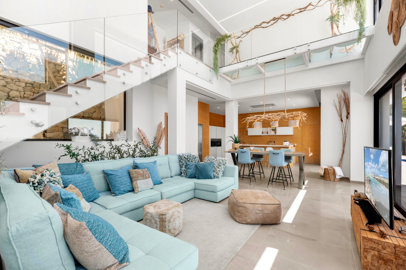 Vaste espace de vie ouvert avec canapé sectionnel bleu clair, escalier moderne en verre et cuisine aux accents de bois chaleureux, baigné de lumière naturelle. Vaste espace de vie ouvert avec canapé sectionnel bleu clair, escalier moderne en verre et cuisine aux accents de bois chaleureux, baigné de lumière naturelle.
