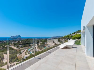Grande terrasse extérieure carrelée de tons clairs, agrémentée d'une chaise longue blanche moderne et d'une balustrade en verre. Profitez des vues panoramiques sur la mer, le Peñón de Ifach et Calpe.