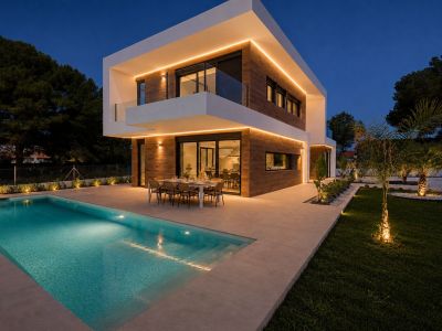 Extérieur de la villa moderne au crépuscule, avec ses lignes architecturales épurées, bardage effet bois et éclairage LED chaleureux. Piscine privée et terrasse repas illuminées, entourées d'un jardin paysager.