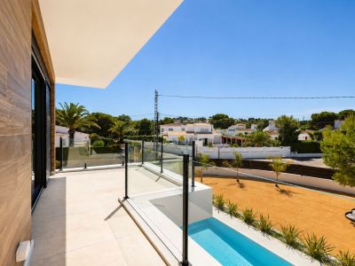 Terrasse supérieure avec carrelage clair, balustrade en verre et vue sur l'urbanisation. Elle intègre une section de piscine linéaire et un mur extérieur en revêtement bois.