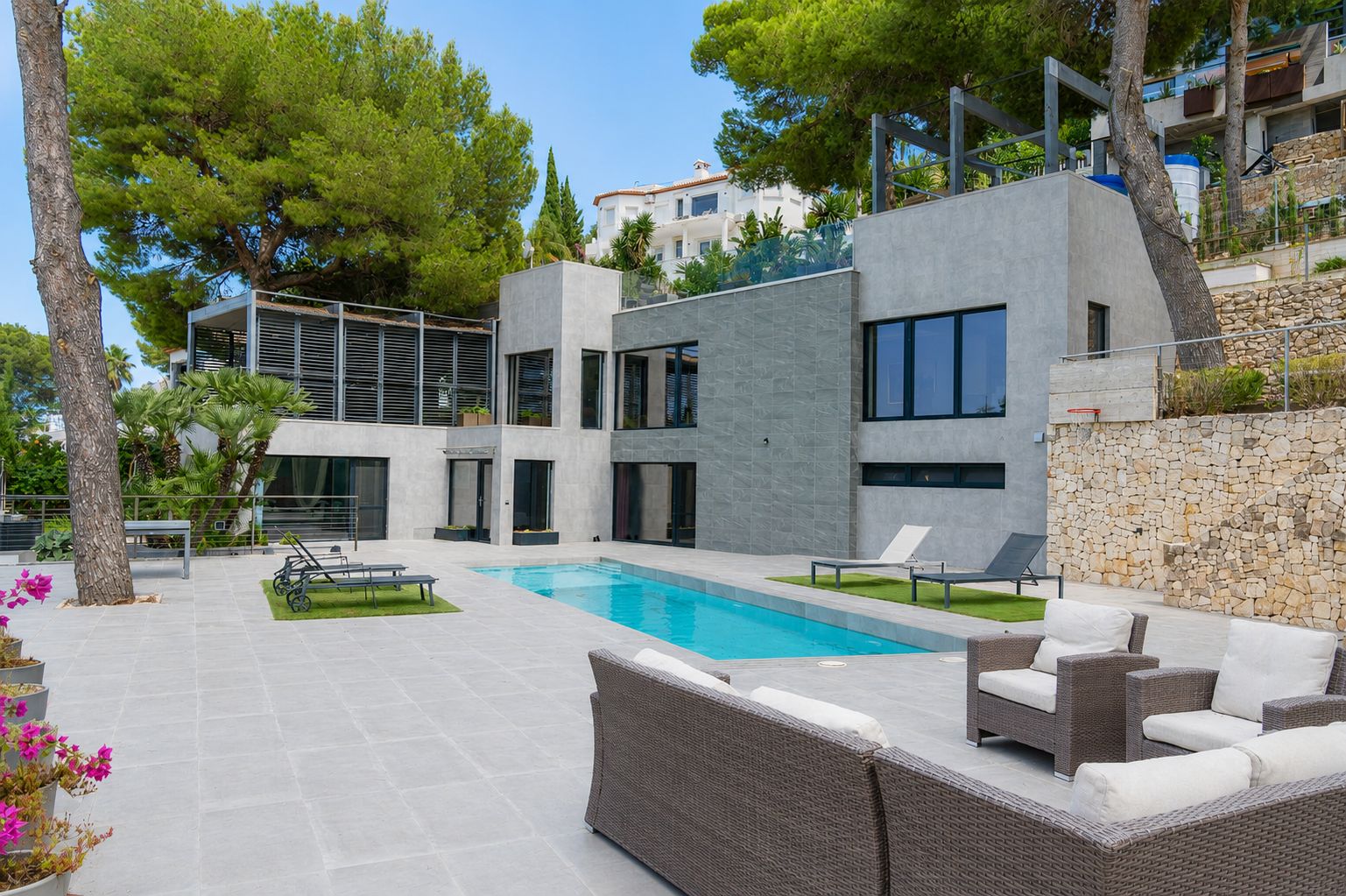 Vaste salon-salle à manger ouvert avec cuisine intégrée moderne. De grandes baies vitrées s'ouvrent sur une terrasse couverte spacieuse offrant des vues panoramiques et une lumière naturelle abondante.