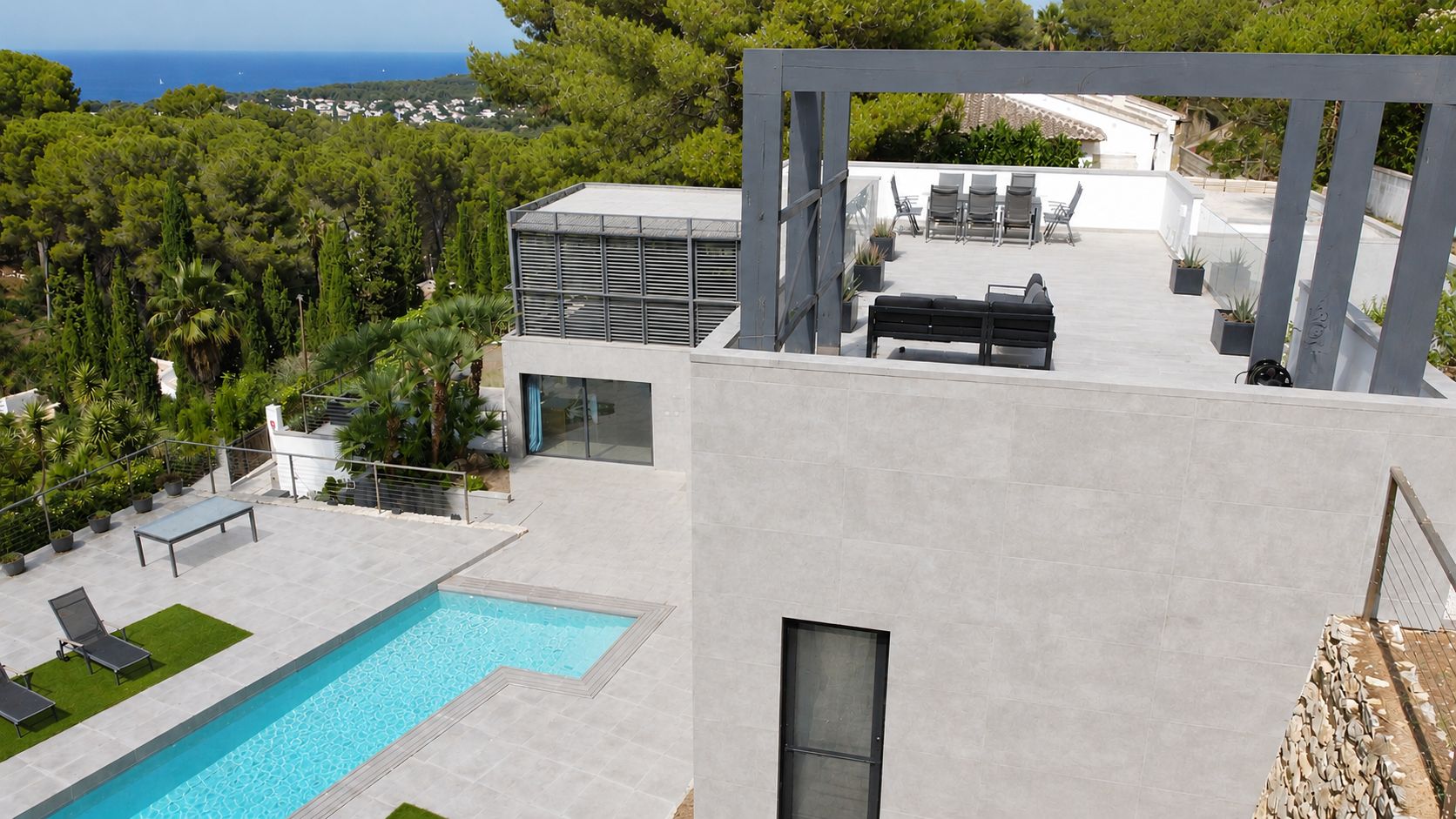 Vue aérienne de la villa moderne, avec piscine privée, grandes terrasses carrelées et espace chill-out surélevé. Profitez des vues sur la mer Méditerranée et la végétation. Design contemporain.