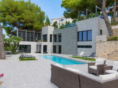 Vaste salon-salle à manger ouvert avec cuisine intégrée moderne. De grandes baies vitrées s'ouvrent sur une terrasse couverte spacieuse offrant des vues panoramiques et une lumière naturelle abondante.