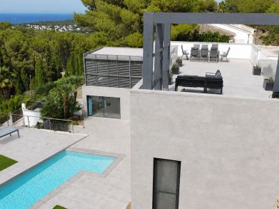 Vue aérienne de la villa moderne, avec piscine privée, grandes terrasses carrelées et espace chill-out surélevé. Profitez des vues sur la mer Méditerranée et la végétation. Design contemporain.