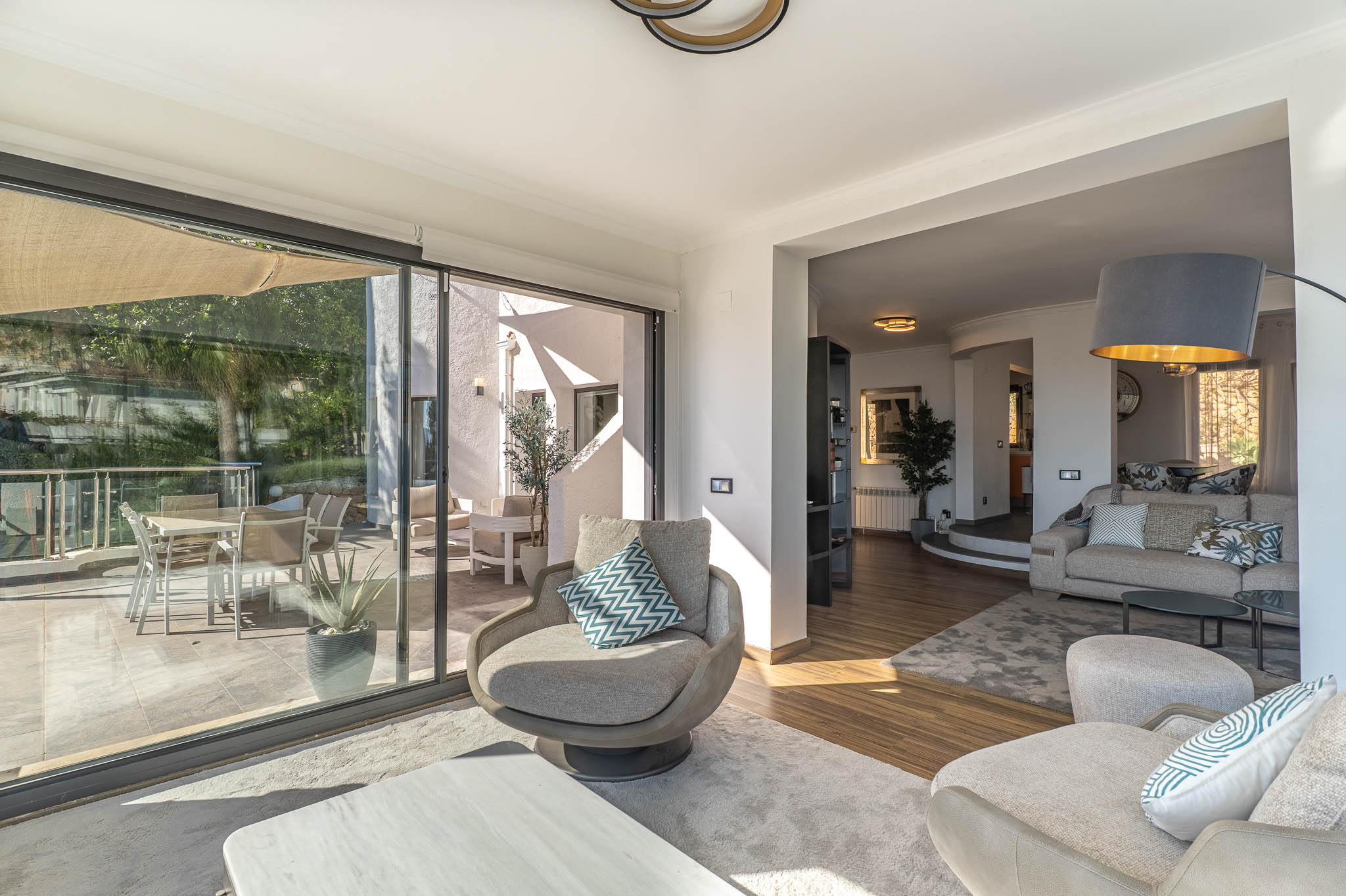 Salon moderne aux larges baies vitrées s'ouvrant sur la terrasse, offrant des vues panoramiques imprenables sur la Méditerranée et inondant l'espace de lumière naturelle.