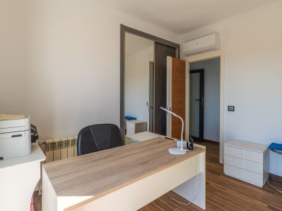 Bureau lumineux avec un bureau imitation bois clair, sol stratifié, armoire coulissante miroir et unité de climatisation murale.