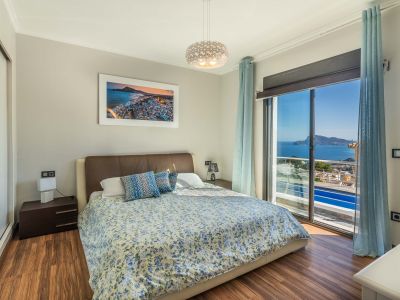 Chambre à coucher avec lit double, parquet stratifié et vue imprenable sur la mer depuis la grande baie vitrée. Armoire miroir intégrée.