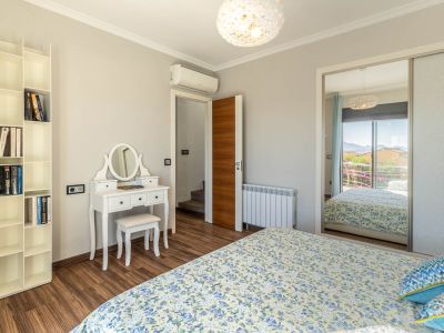 Chambre avec parquet stratifié, coiffeuse blanche et bibliothèque modulaire. L'armoire miroir reflète une vue montagneuse depuis le balcon.