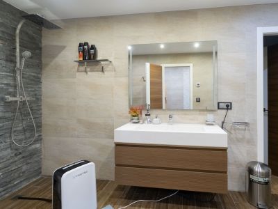 Salle de bain moderne avec douche pluie et mur d'accent en ardoise, meuble vasque suspendu en bois et évier intégré. Carrelage effet bois au sol.