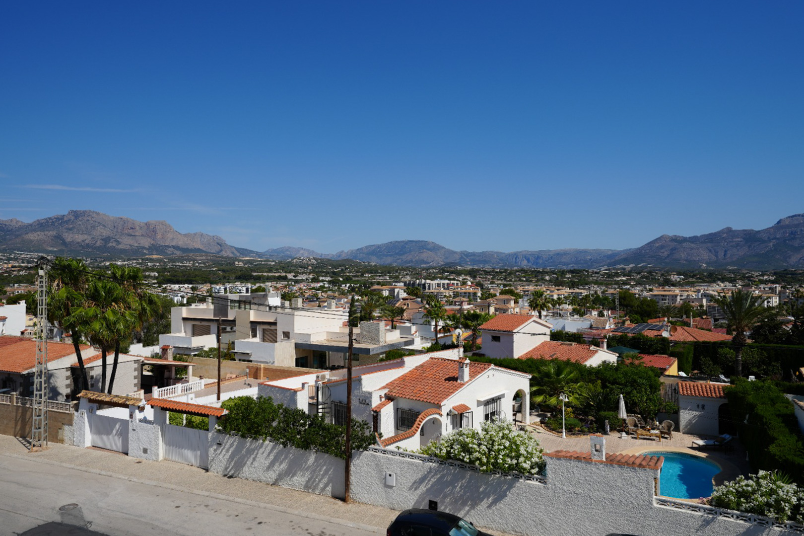 Vue aérienne du quartier résidentiel d'Albir, avec son architecture variée, une végétation luxuriante et une piscine privée, encadrée par les montagnes sous un ciel bleu clair. Vue aérienne du quartier résidentiel d'Albir, avec son architecture variée, une végétation luxuriante et une piscine privée, encadrée par les montagnes sous un ciel bleu clair.