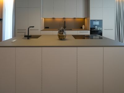 Cuisine design avec îlot central, évier intégré, plaque à induction et mobilier aux tons neutres.