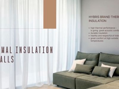 Détail intérieur illustrant l'isolation thermique avancée des murs, avec un canapé d'angle moderne et de fins voilages.