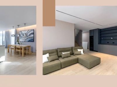 Espace de vie ouvert avec îlot de cuisine moderne, salle à manger en bois et canapé sectionnel vert olive. Rangement intégré gris foncé et éclairage élégant complètent le design.