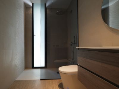 Salle de bain moderne avec meuble-lavabo en bois, miroir rond et douche à l'italienne. Carrelage mural texturé et fenêtre dépolie.