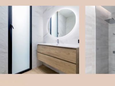 Salle de bain moderne avec meuble vasque flottant en bois, miroir ovale lumineux et douche à effet pluie. Carrelage mural marbré et texturé.
