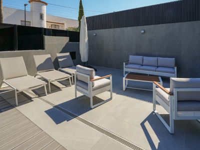 Terrasse extérieure aménagée avec mobilier contemporain blanc et gris, sol en carrelage et platelage composite. Comprend des transats et un salon de jardin.