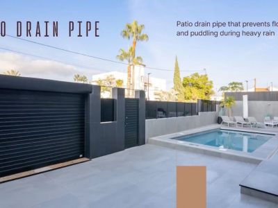 Vaste patio extérieur avec piscine, revêtement de sol carrelé gris clair et porte de garage noire moderne. Un drain de terrasse intégré prévient les inondations.