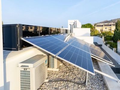 Vaste système de panneaux solaires photovoltaïques sur le toit. Les unités de climatisation et une surface de gravier clair complètent cette installation à haute efficacité.