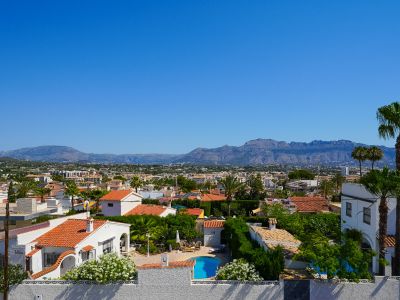 Vue aérienne du quartier résidentiel d'Albir, montrant une piscine privée, des maisons aux toits de tuiles et une végétation méditerranéenne luxuriante, avec les montagnes en toile de fond.