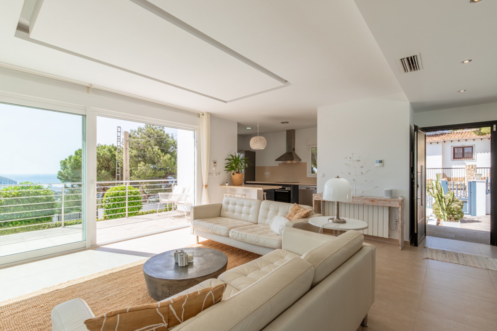 Vaste salon-salle à manger ouvert avec cuisine intégrée, grandes baies vitrées donnant sur un balcon avec vue mer et lumière naturelle. Comprend un radiateur et la climatisation gainable.
