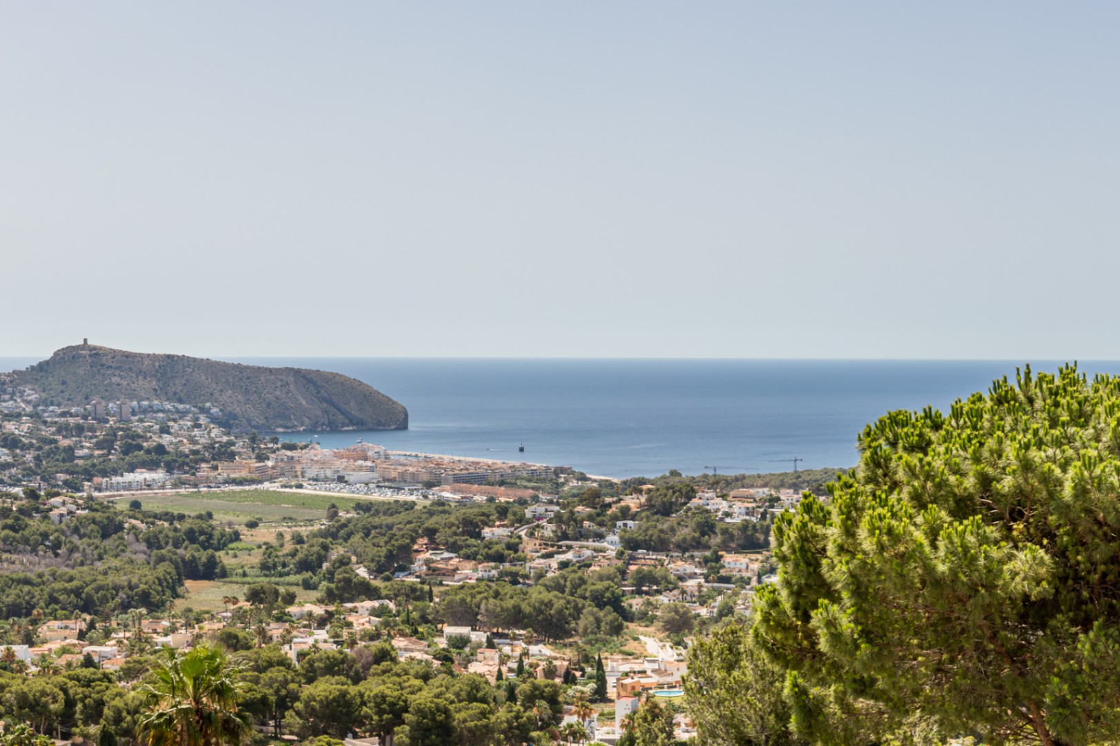 Vue élevée de Moraira depuis Benimeit, avec le Cap d'Or, le littoral méditerranéen et les zones résidentielles arborées.