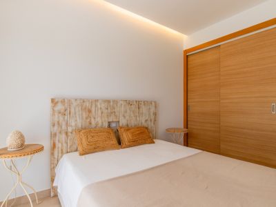Chambre avec tête de lit en bois vieilli, armoire intégrée à portes coulissantes en bois clair et éclairage de plafond discret.