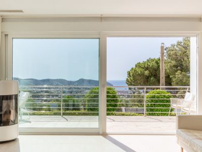 Espace de vie lumineux avec poêle à granulés moderne et grandes baies vitrées donnant sur une terrasse offrant des vues mer et paysagères.