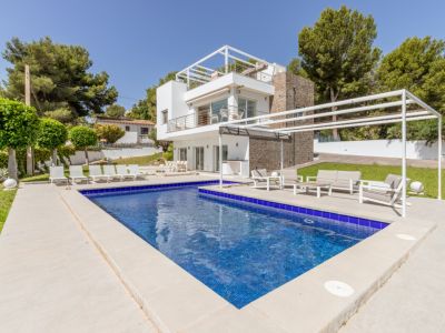 Piscine en mosaïque bleue et terrasse pavée avec espace détente sous pergola, devant la villa moderne aux façades blanches et pierre.