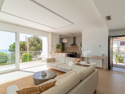 Vaste salon-salle à manger ouvert avec cuisine intégrée, grandes baies vitrées donnant sur un balcon avec vue mer et lumière naturelle. Comprend un radiateur et la climatisation gainable.