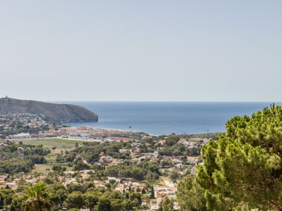 Vue élevée de Moraira depuis Benimeit, avec le Cap d'Or, le littoral méditerranéen et les zones résidentielles arborées.