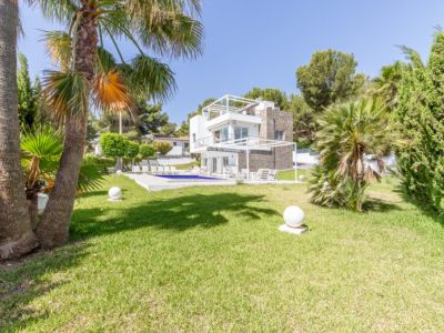 Vue extérieure de la villa moderne à plusieurs niveaux, avec grande piscine, pelouse impeccable, palmiers et luminaires sphériques.