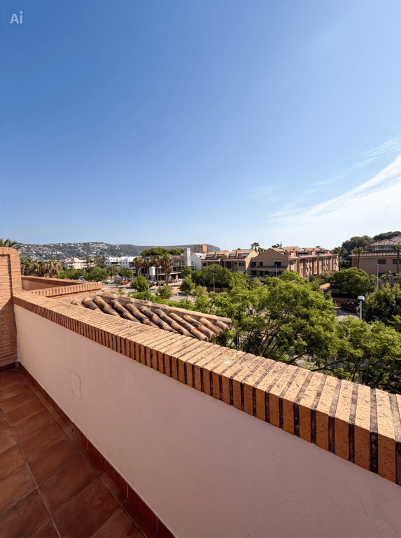 Vaste terrasse avec sol en carreaux de terre cuite et balustrade en briques. Elle offre des vues dégagées sur la zone résidentielle, la verdure et les collines lointaines, avec des tuiles anciennes.
