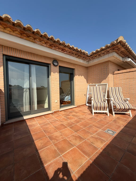 Vaste terrasse supérieure avec carrelage en terre cuite, murs en briques et tuiles traditionnelles. Meublée de deux chaises longues et accès direct aux chambres.
