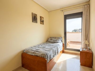 Chambre individuelle avec lit en bois, sol en marbre poli et accès direct à une terrasse supérieure, baignée de lumière naturelle.