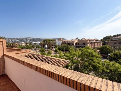 Vaste terrasse avec sol en carreaux de terre cuite et balustrade en briques. Elle offre des vues dégagées sur la zone résidentielle, la verdure et les collines lointaines, avec des tuiles anciennes.