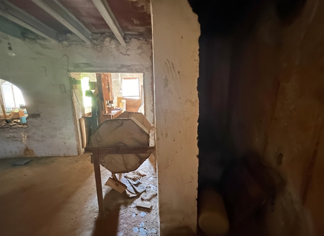 Intérieur en rénovation avec poutres apparentes et murs bruts. Une structure en bois octogonale est visible au centre, avec lumière naturelle au fond. Intérieur en rénovation avec poutres apparentes et murs bruts. Une structure en bois octogonale est visible au centre, avec lumière naturelle au fond.