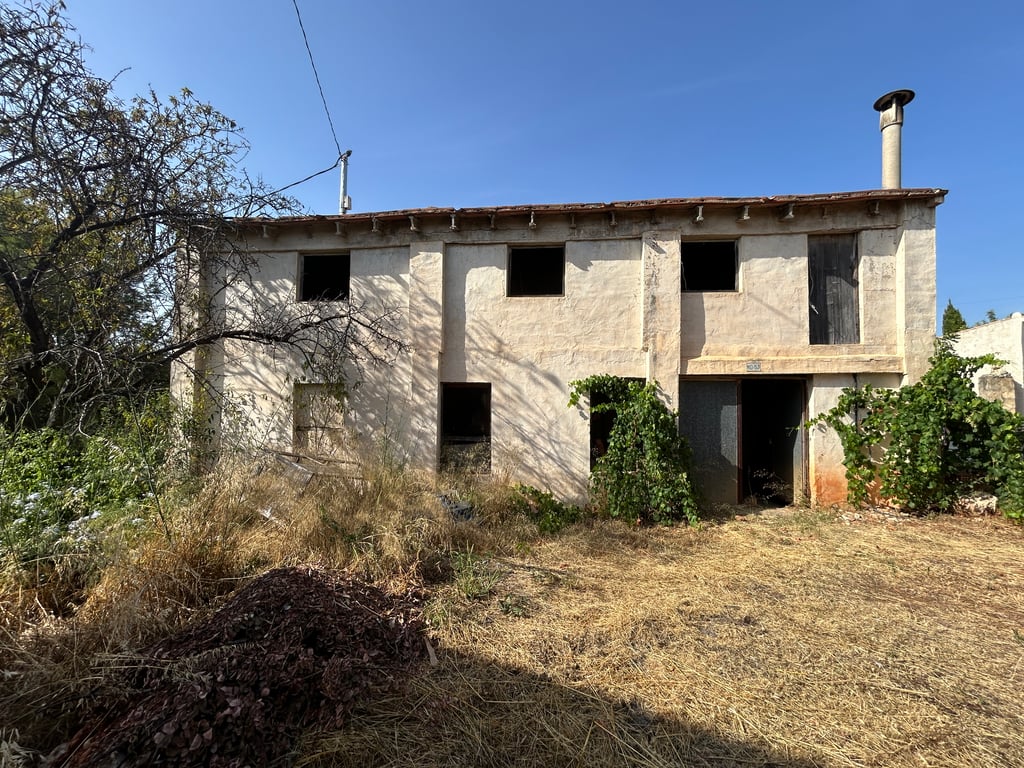 Vue extérieure d'une maison traditionnelle à deux étages avec façade enduite, plusieurs ouvertures de fenêtre sans vitrage et une vieille porte en bois. Le toit et les abords nécessitent une rénovation complète. Vue extérieure d'une maison traditionnelle à deux étages avec façade enduite, plusieurs ouvertures de fenêtre sans vitrage et une vieille porte en bois. Le toit et les abords nécessitent une rénovation complète.