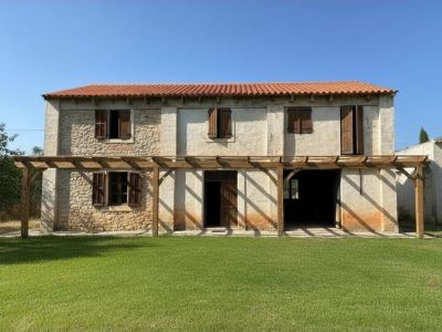 Façade principale à deux étages avec un toit en tuiles rouges, des murs en pierre et enduits, et une pergola en bois au-dessus de la pelouse.