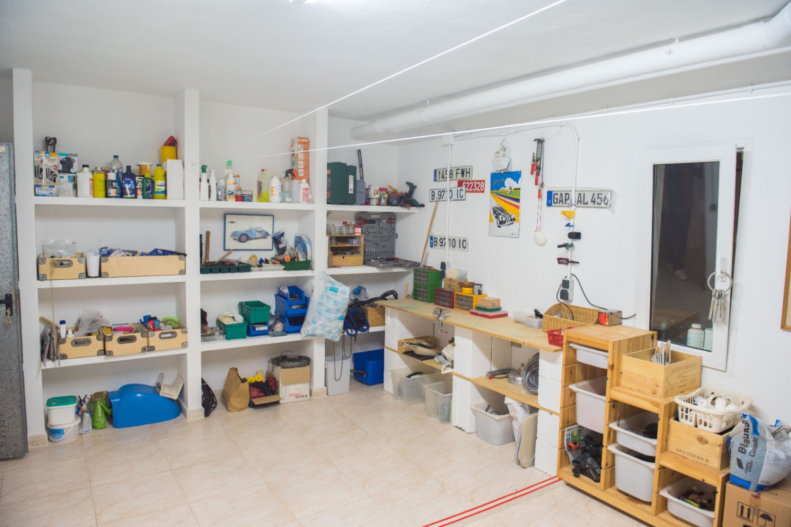 Atelier et espace de rangement spacieux avec étagères intégrées en maçonnerie, établi en bois et sol carrelé pour l'entretien et le bricolage.