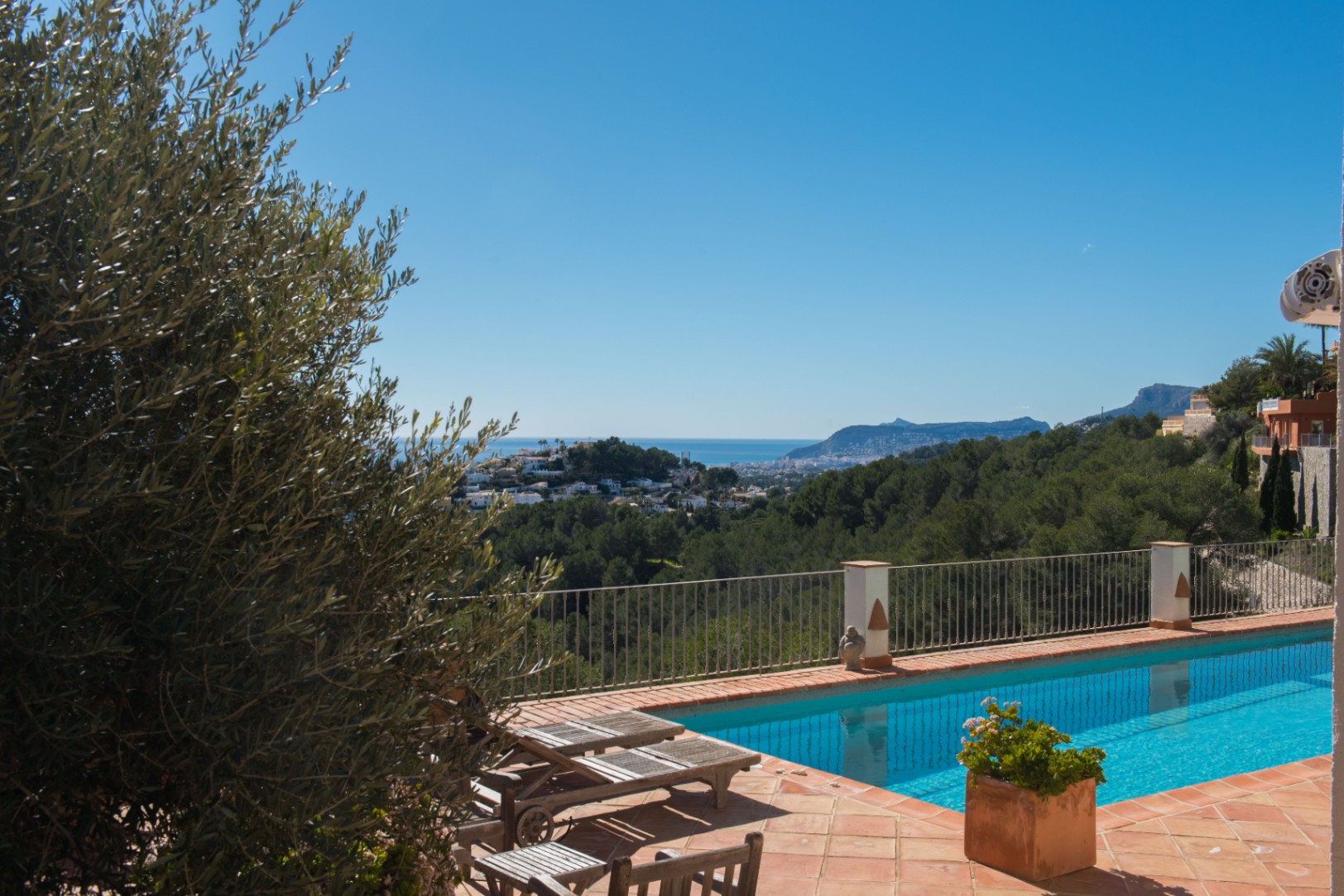 Terrasse en terre cuite avec piscine privée, offrant une vue dégagée sur la côte méditerranéenne, le rocher d'Ifach et la forêt de pins environnante.