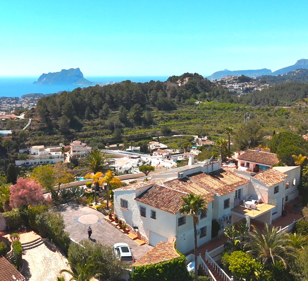 Vue aérienne de la villa méditerranéenne aux toits de tuiles, entourée de jardins luxuriants avec une vue panoramique sur la mer et le Peñón de Ifach.