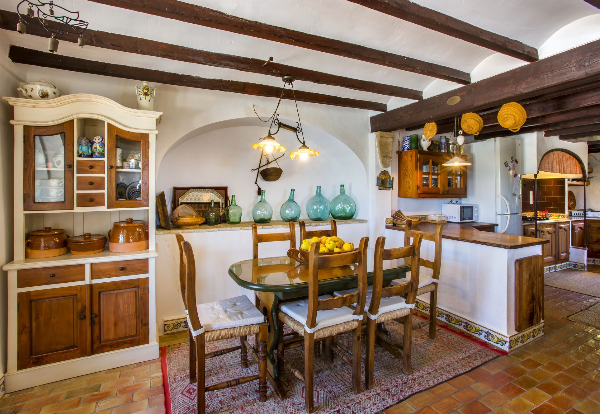Salle à manger rustique avec table ovale, chaises en bois et buffet de style traditionnel. Poutres apparentes au plafond.