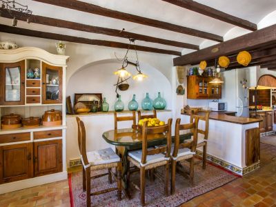Salle à manger rustique avec table ovale, chaises en bois et buffet de style traditionnel. Poutres apparentes au plafond.